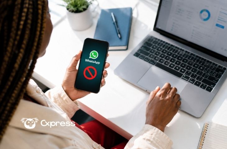 Mujer sosteniendo el celular con WhatsApp bloqueado en la pantalla mientras usa su laptop con un panel de análisis abierto